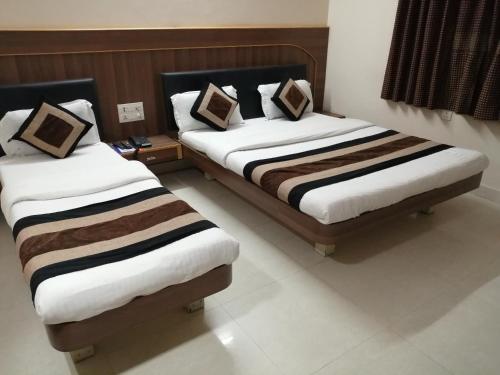 two beds in a hotel room withskirts at Hotel Nandnandan in Dwarka