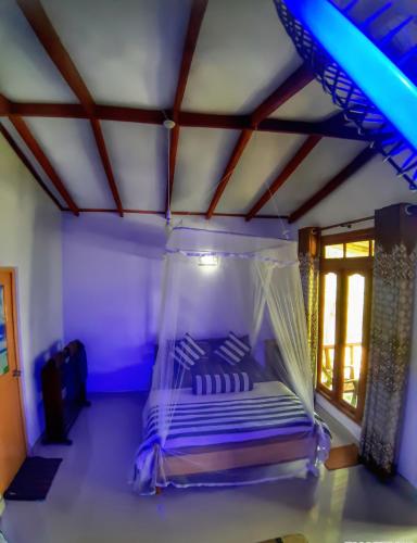 a bedroom with a bed with a mosquito net at Cozy Homestay Waterfall Road Ella in Ella