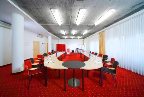 a room with tables and chairs in a room with red carpet at Altstadthotel Arte in Fulda