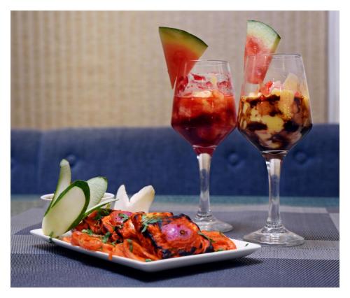 two glasses of wine and a plate of food on a table at Udaan Olive Hotel & Spa, Pelling in Pelling
