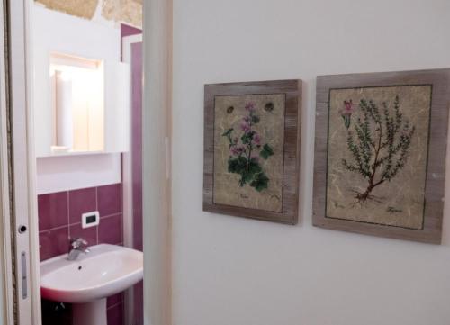 een badkamer met twee foto's aan de muur en een wastafel bij La casetta in Terrasini