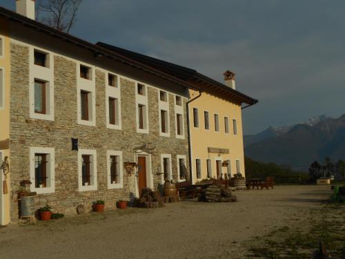 a large stone building with mountains in the background at Agriturismo La Casa Nei Boschi in Colderù