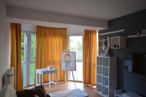 a living room with orange curtains and a painting at M@D Apartment in Timişoara
