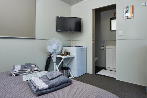 Habitación con 1 cama con ventilador y TV. en WanaHaka - Lake Wanaka & Town at your door en Wanaka
