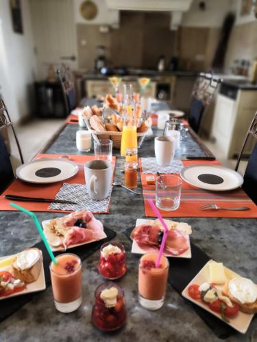 a long table with plates of food and drinks at Chambre d'hôtes du Mas de Longuefeuille in Malaucène