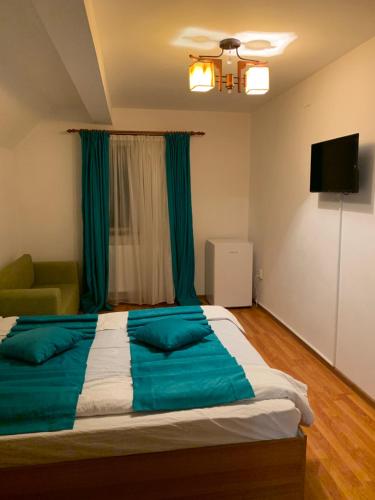 a bedroom with a large bed with blue sheets at Casa Galbena in Slănic