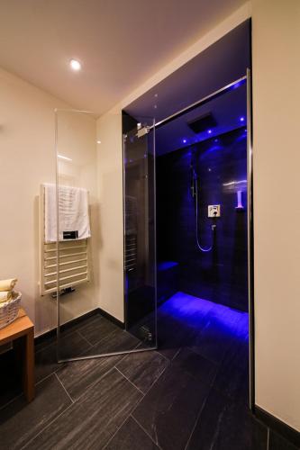 a bathroom with a glass shower with blue lighting at Hotel Tirol in Ischgl
