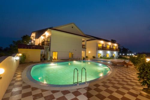 a swimming pool in front of a house at night at Hotel Earth Light Sauraha in Chitwan