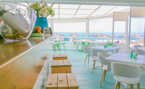 a restaurant with tables and white chairs and windows at Lovely Burgau villa just 3 mins walk from beach in Budens