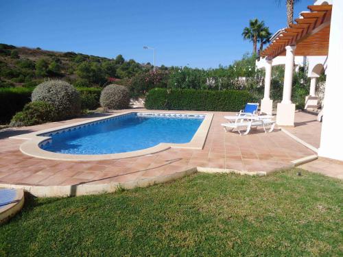 a swimming pool with two chairs and a patio at Lovely Burgau villa just 3 mins walk from beach in Budens