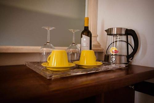 a table with two yellow cups and a bottle of wine at Camere Nicolina in Vernazza