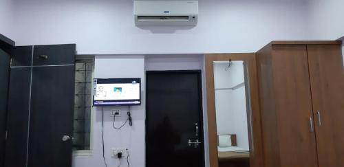 a room with a door and a television and a room with a cabinet at Rajhuns Deluxe Lodging in Kolhapur