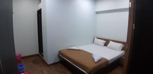 a small bedroom with a bed with white sheets and pillows at Rajhuns Deluxe Lodging in Kolhapur