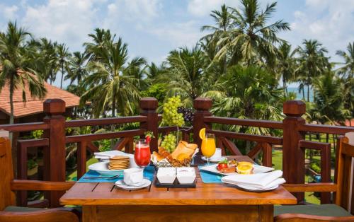 a table topped with plates of food on top of a wooden bench at Royal Palms Beach Hotel in Kalutara