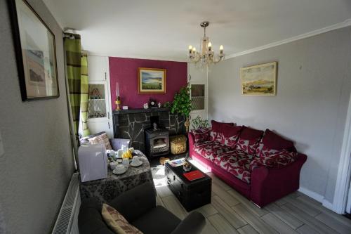 a living room with a red couch and a fireplace at Kings Accommodation in Donegal