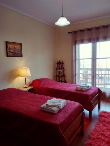 a bedroom with two beds with red sheets and a window at Sofia's House in Litochoro