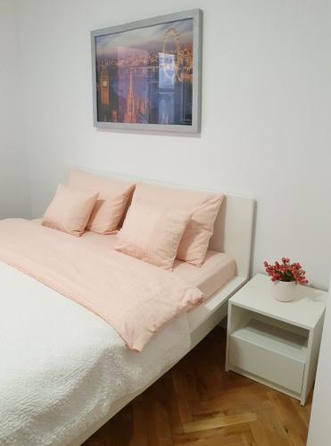 a bedroom with a white bed with pink pillows at Lovely Private Flats FREE parking in Novi Sad