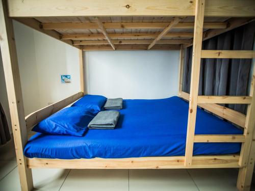 a bunk bed with blue sheets and a wooden ladder at Iskandar Puteri Medini Famous Theme Park in Nusajaya