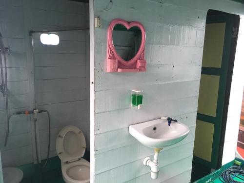 W łazience znajduje się umywalka, toaleta i lustro. w obiekcie Orang Utan Houseboat 2 w mieście Kumai