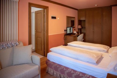 a hotel room with two beds and a chair at Hotel Compagnoni in Livigno