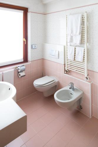 a pink bathroom with a toilet and a sink at Hotel Compagnoni in Livigno
