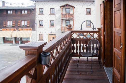 a wooden balcony with a chair and a view of a building at Hotel Compagnoni in Livigno