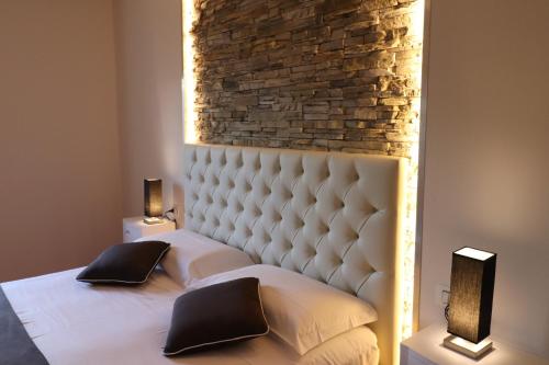 a bedroom with a white bed with a brick wall at Borgo di Villa Cellaia Resort & SPA in Dicomano