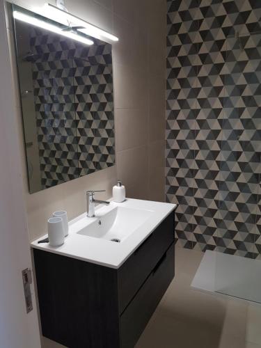 een badkamer met een wastafel en een spiegel bij Casinha Manta in Salema