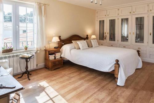 Un dormitorio con una gran cama blanca y un escritorio. en Villa Gerbera, en Apostiça
