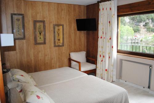 a bedroom with a bed and a window and a chair at Hotel Casa Julián in Peñamellera Alta