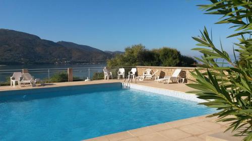 ein Swimmingpool mit Liegen und Blick aufs Wasser in der Unterkunft Les Sables Blancs de la Liscia in Calcatoggio
