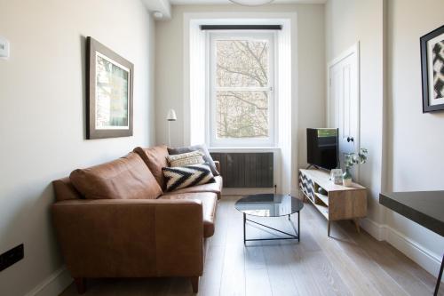 een woonkamer met een bruine bank en een tv bij Holyrood Park City Centre Apartment in Edinburgh