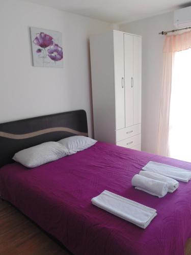 um quarto com uma cama roxa com toalhas em Apartments Luna em Bar