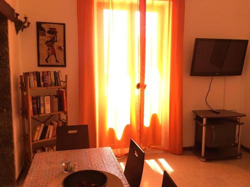 Habitación con mesa y ventana con cortinas de color naranja. en Casa Bucalo, en Taormina