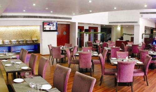 un restaurante con mesas y sillas de color púrpura y un bar en The Aures (formerly known as Keys Select The Aures), en Aurangabad