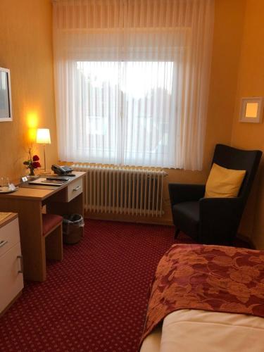 a hotel room with a bed and a desk and a window at Thermen Hotel Pension Villa Holstein in Bad Salzuflen