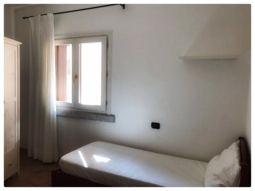 biały pokój z łóżkiem i oknem w obiekcie Incanto Apartment Golfo Aranci w mieście Golfo Aranci