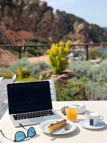 a laptop computer sitting on a table with a plate of food at Hotel Costa Paradiso in Costa Paradiso