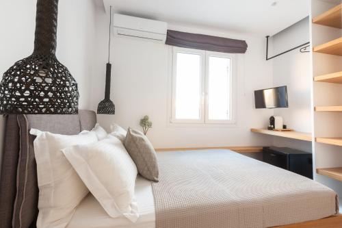 a bedroom with a bed with white pillows and a window at Eleana Hotel in Tinos Town