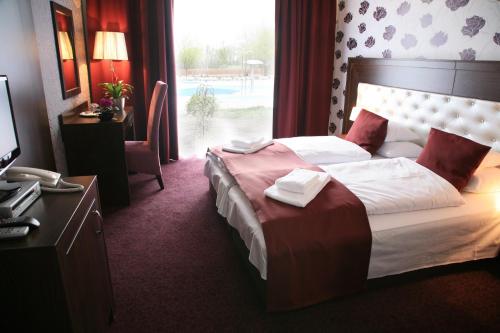 a hotel room with a bed and a desk with a computer at Session Hotel Ráckeve in Ráckeve