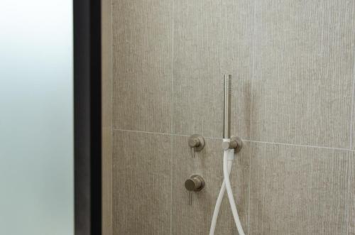 a shower with a glass door with a wand at Eleana Hotel in Tinos Town