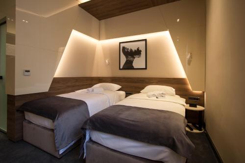 two beds in a room with lights on the wall at BOUTIQUE 25h by Eva stay 018 in Niš
