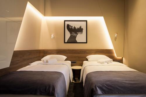 two beds in a room with lights on the wall at BOUTIQUE 25h by Eva stay 018 in Niš