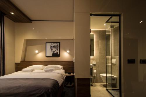 um quarto com uma cama e uma casa de banho com um chuveiro em Garni Hotel Boutique 25h em Niš