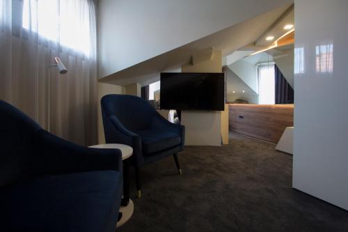 a living room with a blue chair and a tv at BOUTIQUE 25h by Eva stay 018 in Niš