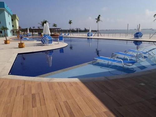 a swimming pool with blue chairs and the beach at Pedaço do Paraíso em Arraial do Cabo in Arraial do Cabo