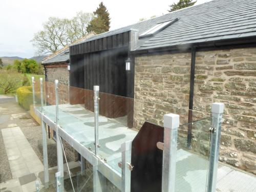 a glass table in front of a stone building at Auchendennan Farm Self Catering Cottages in Balloch