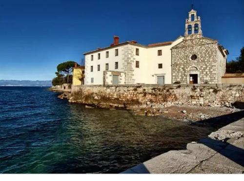 a building on the side of a body of water at Apartman Nicolle in Krk