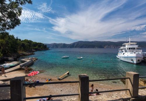 a cruise ship is docked at a beach with people at Apartman Nicolle in Krk