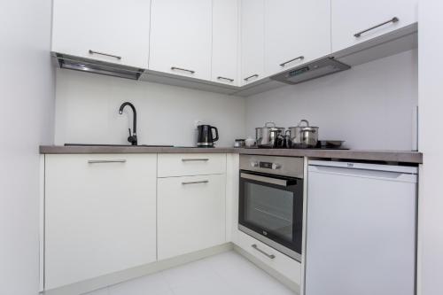 una cocina con armarios blancos y electrodomésticos de acero inoxidable en CR Kameralny Apartament przy Pałacu Branickich, en Białystok